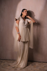 Model wearing a designer ivory embroidered peplum sharara suit set for wedding and festive occasions.
